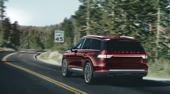 A 2024 Lincoln Aviator® SUV is being driven on a winding mountain road | Empire Lincoln of Huntington in Huntington NY